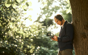 Picture of a person living with epilepsy listening to a podcast in a park
