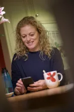 Picture of a person having a coffee and chatting on her phone