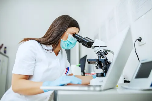 Picture of a woman  looking into a microscope